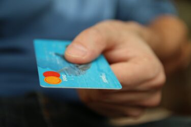 A man handing over a credit card. Any creditor can garnish your wages in alberta.