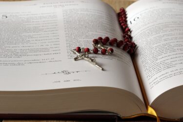 rosary on top of opened bible book. Catholic Schools are free in Alberta.