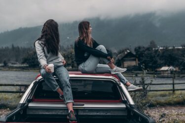 two women sitting on vehicle roofs. yes, You can drive after midnight with a class 5 gdl in alberta.