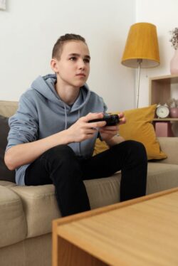 Teen playing video games on couch. Yes 13 and 14 year olds can work in alberta.