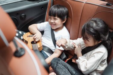 kids sitting in the back seat of a car. kids can sit in the front seat of a vehicle if they are properly secure in alberta.