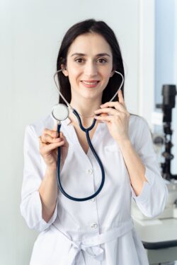 woman smiling while holding a stethoscope. yes you can register to work as a nurse in alberta.