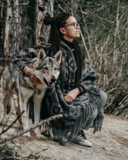 woman petting a wolf in the wild. You can not own a pure wolf breed as a pet in Alberta.