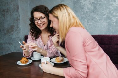 two women looking on smartphone. You can record a conversation in alberta, canada under certain circumstances.