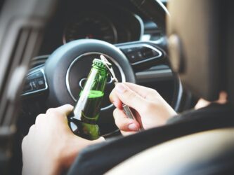 person opening beer bottle in car. maximum bac is .05 to .079 in alberta. bac .08 federally across canada.