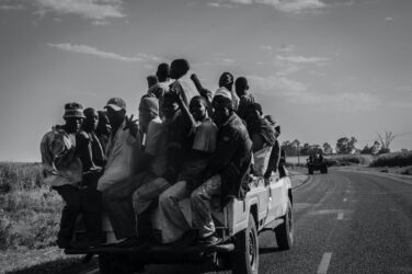 Group of people riding in back of pickup truck. It is illegal in Alberta to have passengers riding outside of the vehicle.