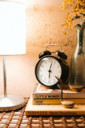 vintage alarm clock and luminous lamp placed on bedside table. Answering “are Alberta and Saskatchewan on the same time zone?”