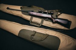 black rifle with scope and brown gig bag. Talking about the various age limits for hunting in alberta.