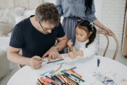 foster parents and child making a drawing on a white paper. How to become a foster parent in alberta, canada.