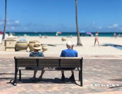man and woman sitting on brown wooden bench retired on the beach. Best places to retire in Alberta, Canada.