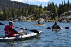 three men riding kayaks on body of water. Where you can kayak in Alberta, Canada.